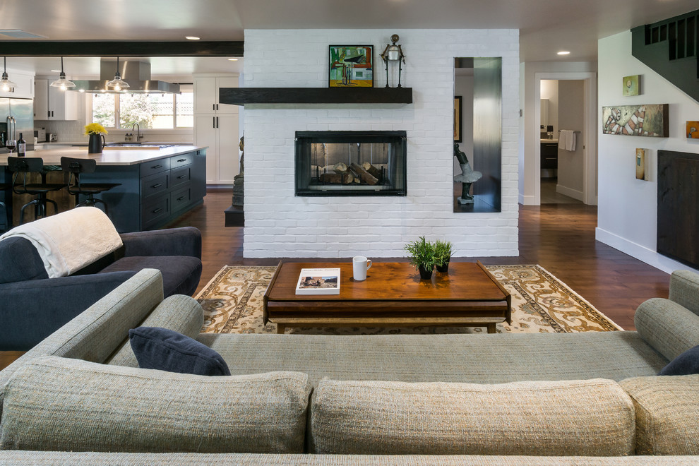 Large retro open plan living room in Portland with white walls, dark hardwood flooring, a two-sided fireplace and a brick fireplace surround.
