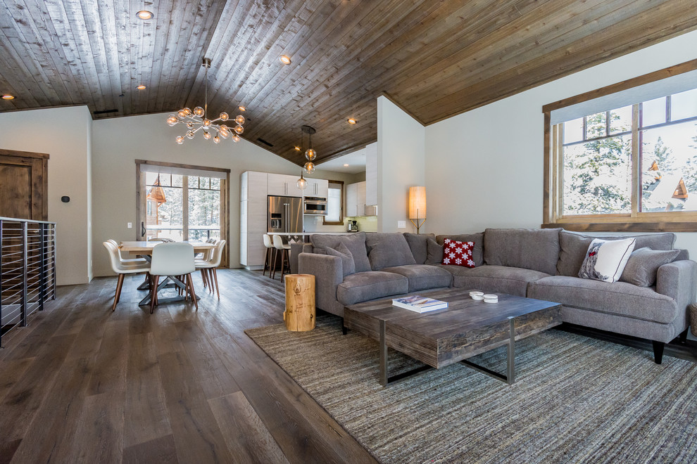 Medium sized rustic open plan living room in Other with grey walls, medium hardwood flooring, a corner fireplace, a stone fireplace surround, a wall mounted tv and grey floors.