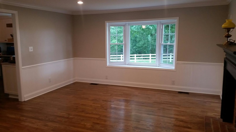 Cette image montre un grand salon chalet ouvert avec un mur gris, un sol en bois brun, une cheminée standard, un manteau de cheminée en brique, aucun téléviseur et un sol marron.