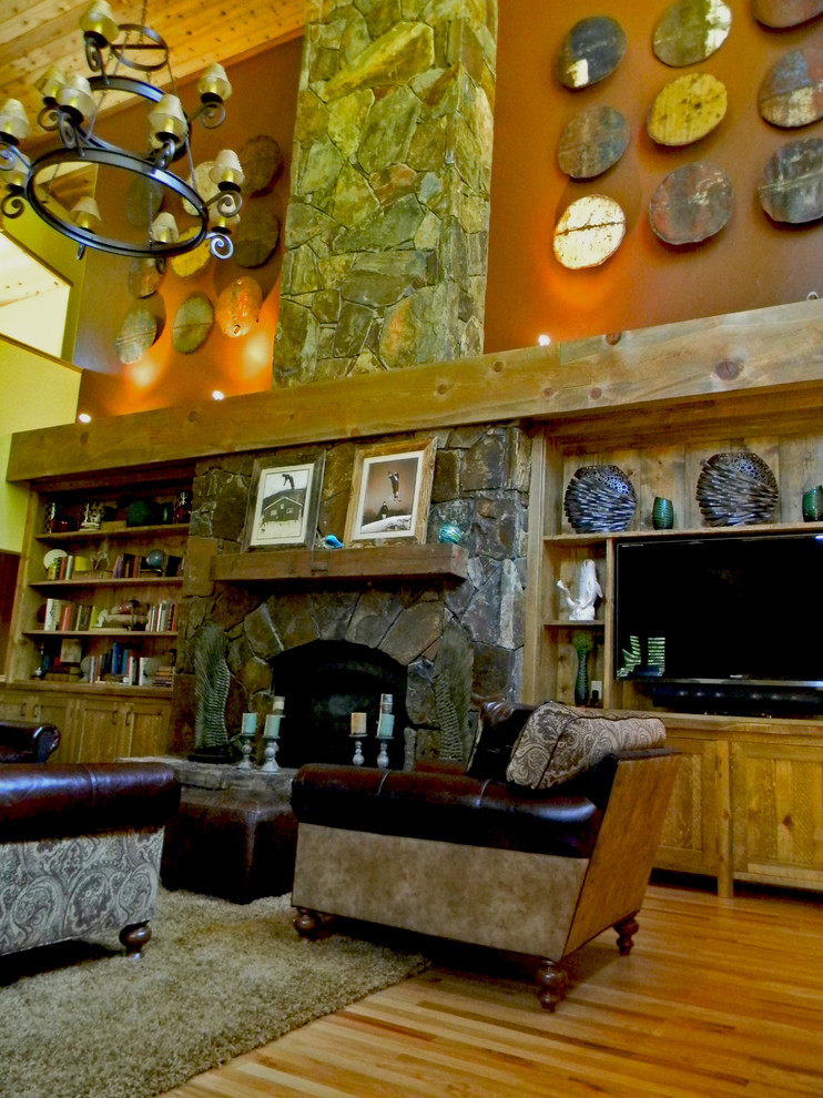 Inspiration pour un grand salon chalet ouvert avec un mur multicolore, parquet clair, un poêle à bois, un manteau de cheminée en pierre et un téléviseur encastré.
