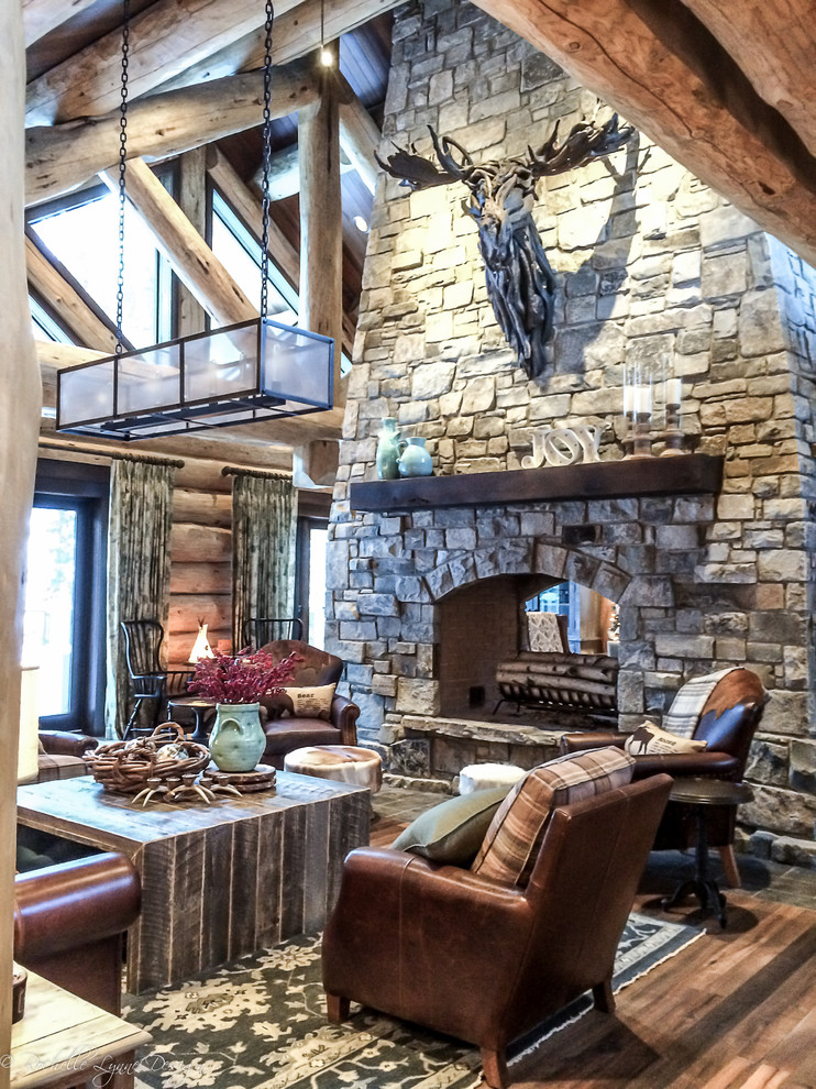 Inspiration for a large rustic open concept medium tone wood floor living room remodel in Calgary with a two-sided fireplace and a stone fireplace
