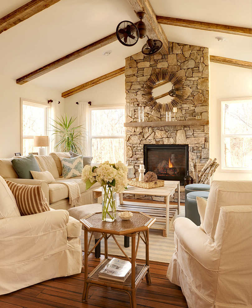 Beach style formal living room in Charlotte with white walls, dark hardwood flooring, a standard fireplace, a stone fireplace surround and feature lighting.