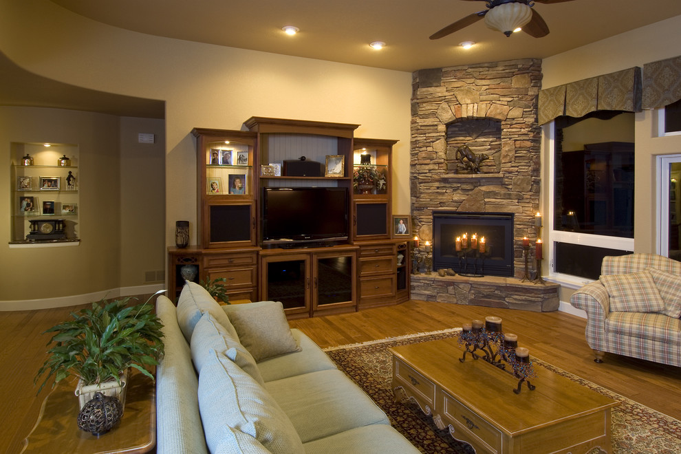 Mittelgroßes, Offenes Klassisches Wohnzimmer mit beiger Wandfarbe, braunem Holzboden, Eckkamin, Kaminumrandung aus Stein und Multimediawand in Denver