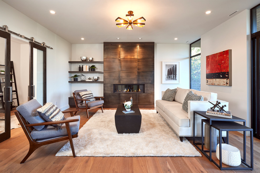 Design ideas for a large contemporary formal open plan living room in San Francisco with white walls, medium hardwood flooring, a standard fireplace, a metal fireplace surround and no tv.