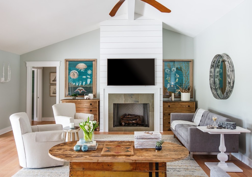 На фото: гостиная комната в морском стиле с серыми стенами, светлым паркетным полом, стандартным камином и телевизором на стене с