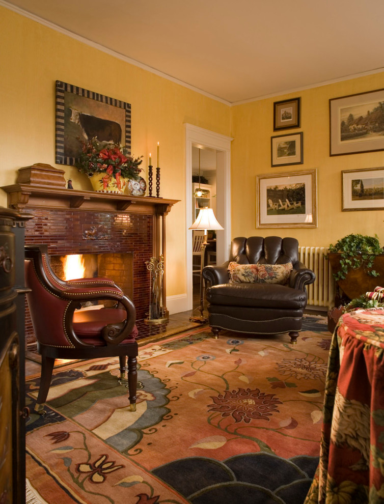 Cette photo montre un petit salon chic avec une salle de réception, un mur jaune, une cheminée standard, un manteau de cheminée en carrelage, un sol en bois brun et un téléviseur fixé au mur.