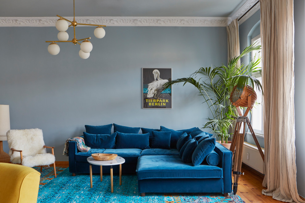 Imagen de salón bohemio con paredes azules, suelo de madera en tonos medios y suelo marrón