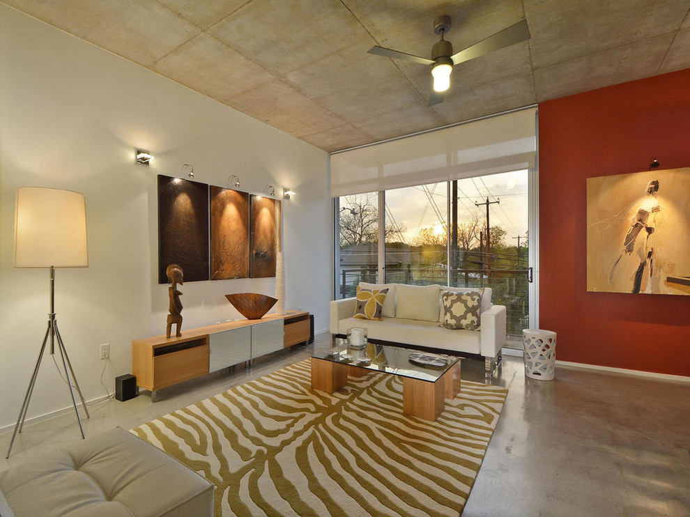 Foto de salón para visitas actual sin chimenea y televisor con paredes rojas y suelo de cemento