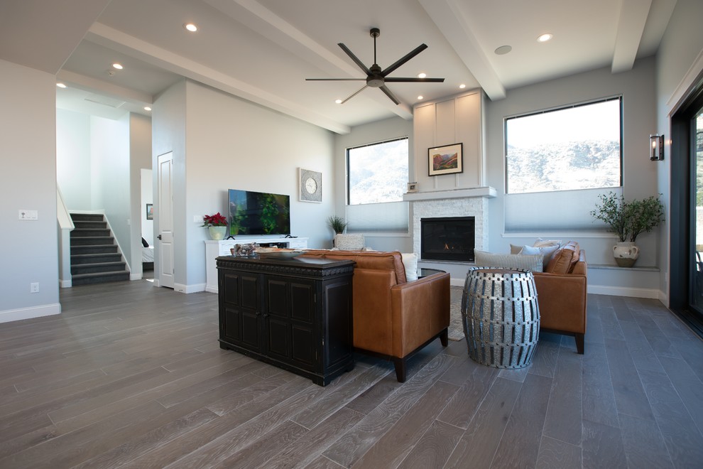 Exemple d'un salon nature ouvert avec un mur gris, parquet clair, une cheminée standard, un manteau de cheminée en pierre et un sol marron.
