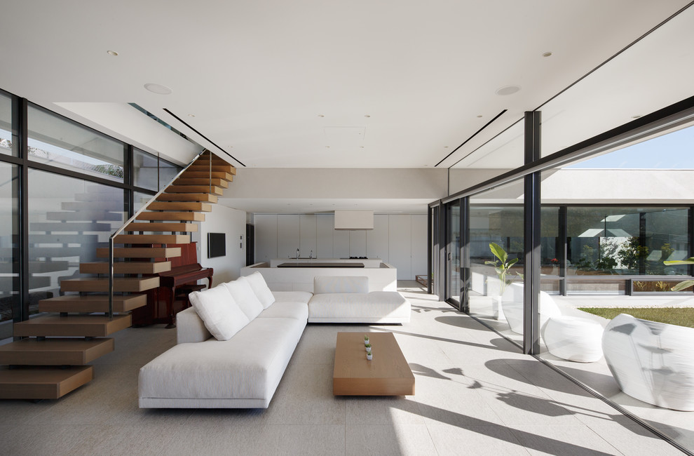 Example of a large minimalist open concept gray floor and ceramic tile living room design in Kobe with white walls, a wall-mounted tv and no fireplace