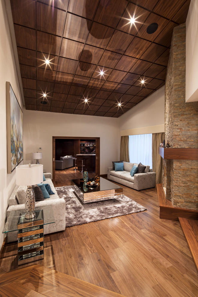 Foto di un soggiorno design aperto con pareti beige, pavimento in legno massello medio, camino ad angolo e cornice del camino in pietra