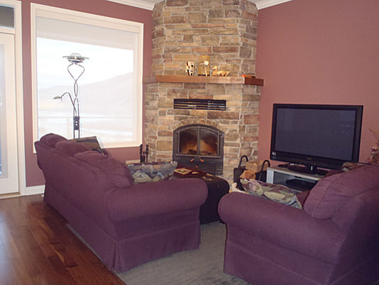 Mittelgroßes, Offenes Modernes Wohnzimmer mit rosa Wandfarbe, dunklem Holzboden, Eckkamin, Kaminumrandung aus Stein und freistehendem TV in Vancouver