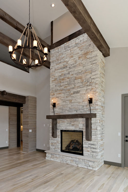 Example of a large mountain style open concept light wood floor and beige floor living room design in Minneapolis with beige walls, a standard fireplace, a stone fireplace and a wall-mounted tv