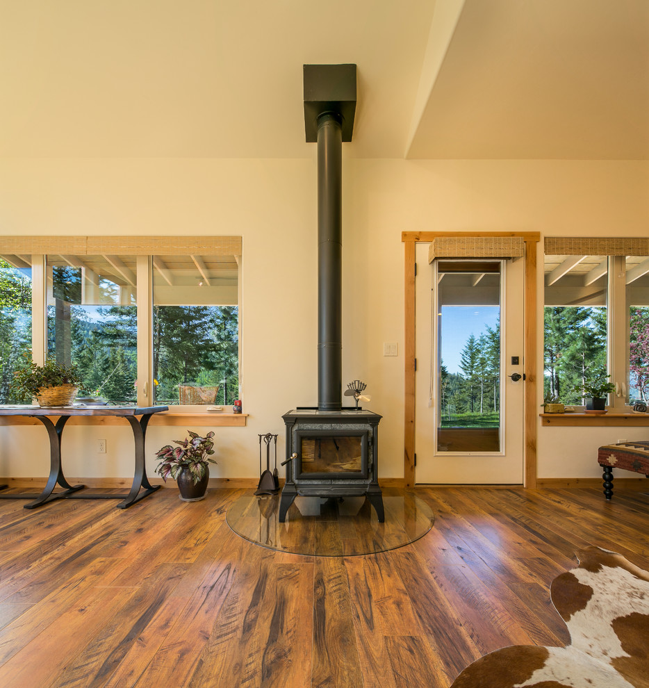 Immagine di un soggiorno stile rurale di medie dimensioni e aperto con pareti beige, pavimento in legno massello medio e stufa a legna