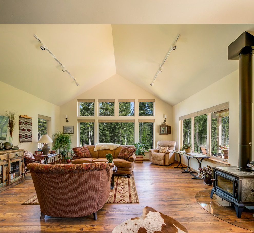 Foto di un soggiorno stile rurale di medie dimensioni e aperto con pareti beige, pavimento in legno massello medio, stufa a legna e TV a parete