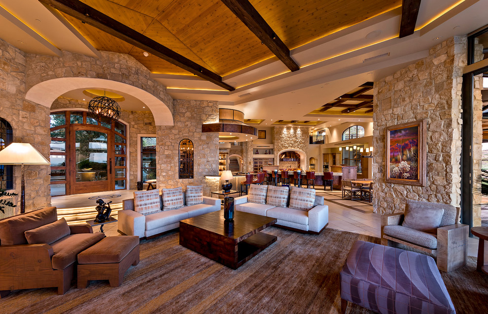 Cette image montre un très grand salon design ouvert avec un bar de salon, un mur multicolore, un sol en travertin et un téléviseur encastré.