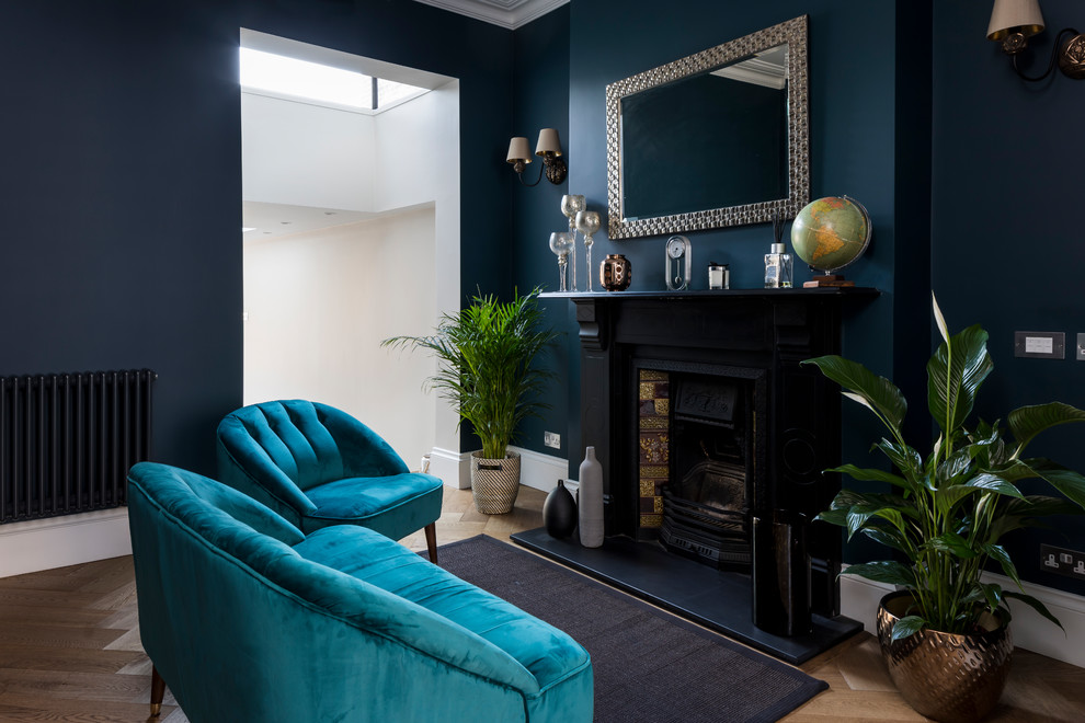 Idee per un piccolo soggiorno design con pareti blu, camino classico e pavimento marrone