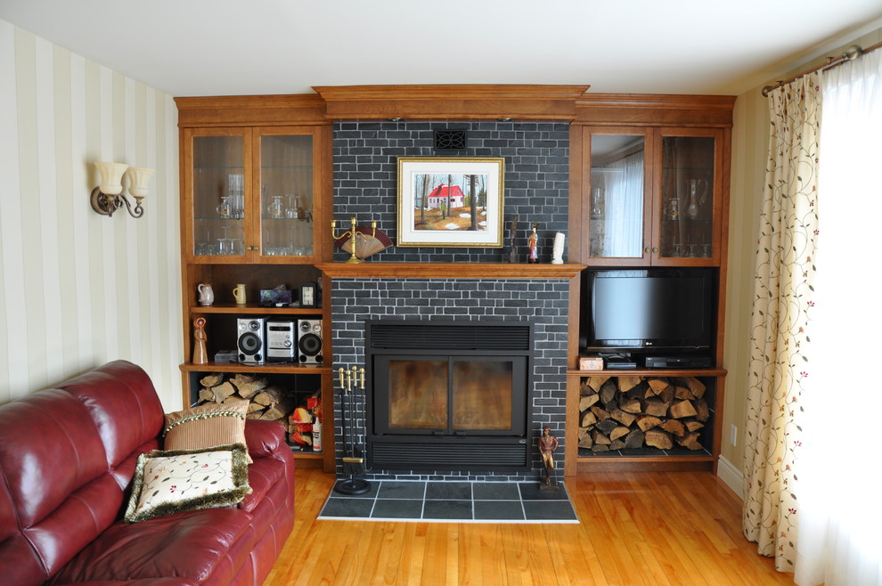Пример оригинального дизайна: гостиная комната в современном стиле с с книжными шкафами и полками, коричневыми стенами, полом из сланца, стандартным камином, фасадом камина из камня и телевизором на стене