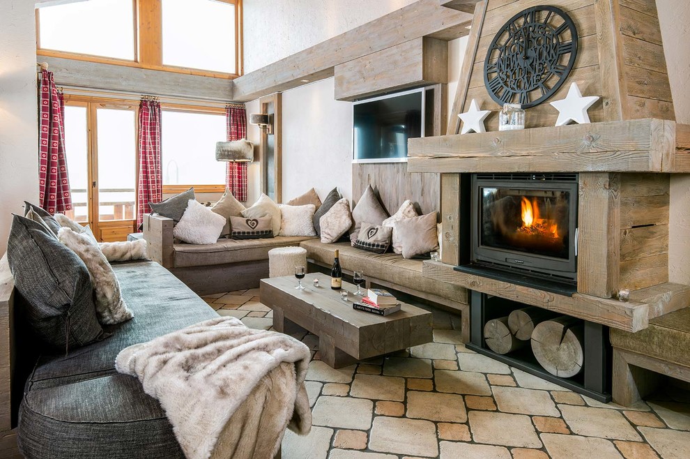 Idée de décoration pour un salon chalet ouvert avec un mur blanc, un poêle à bois, un téléviseur fixé au mur, un manteau de cheminée en bois et éclairage.
