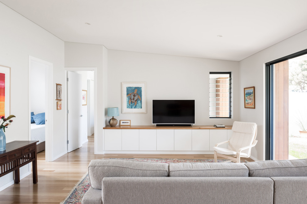 На фото: открытая гостиная комната в современном стиле с белыми стенами, светлым паркетным полом, отдельно стоящим телевизором, бежевым полом и сводчатым потолком