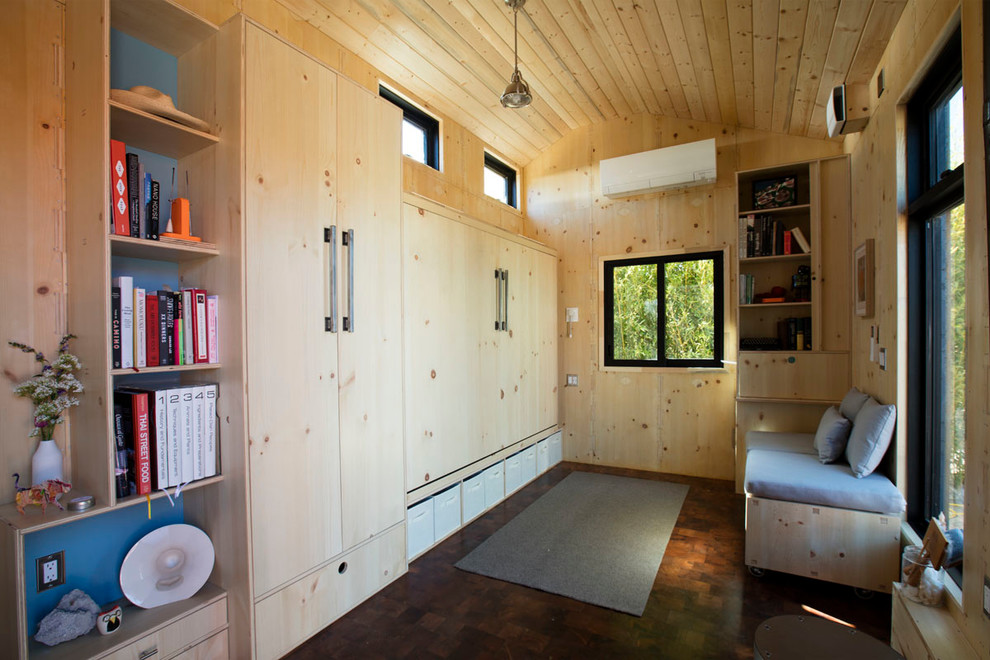Esempio di un piccolo soggiorno design aperto con libreria, pareti beige, parquet scuro, stufa a legna, cornice del camino in metallo, nessuna TV e pavimento marrone