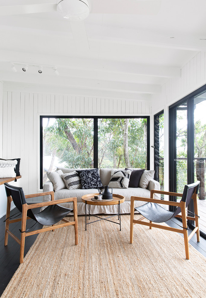 Maritimes Wohnzimmer mit weißer Wandfarbe, gebeiztem Holzboden und schwarzem Boden in Sunshine Coast