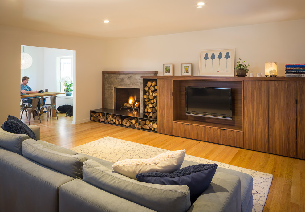 Cette photo montre un salon tendance de taille moyenne et ouvert avec un mur beige, un sol en bois brun, une cheminée standard, un téléviseur encastré et un manteau de cheminée en béton.