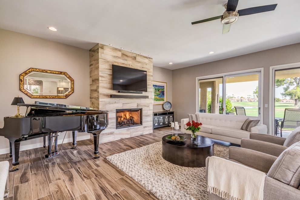 Medium sized contemporary open plan living room in Phoenix with grey walls, porcelain flooring, a standard fireplace, a tiled fireplace surround, a wall mounted tv and beige floors.