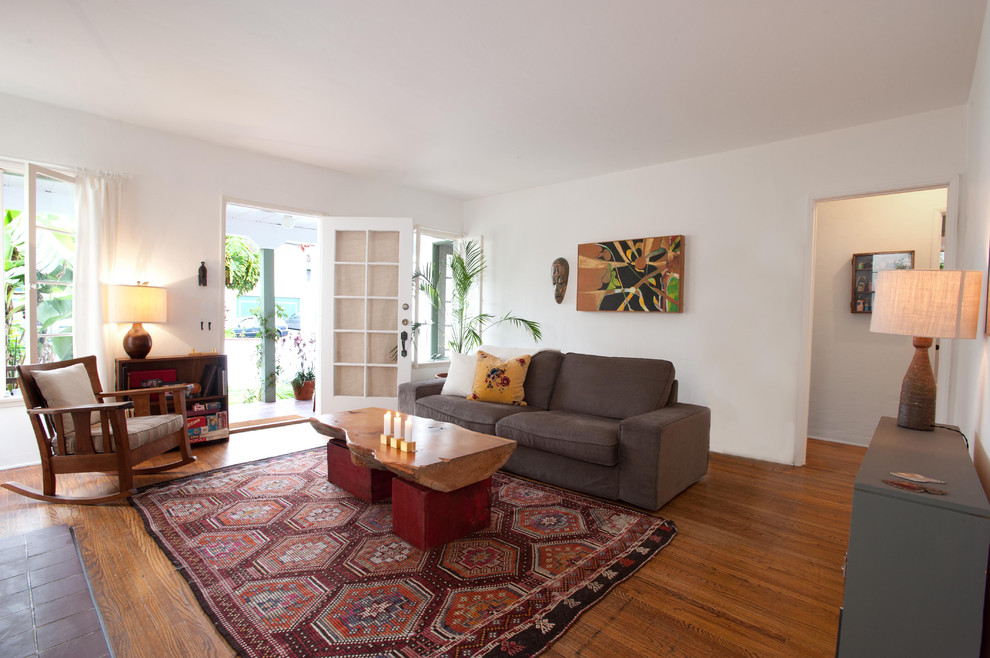 На фото: изолированная гостиная комната в стиле рустика с белыми стенами и коричневым диваном