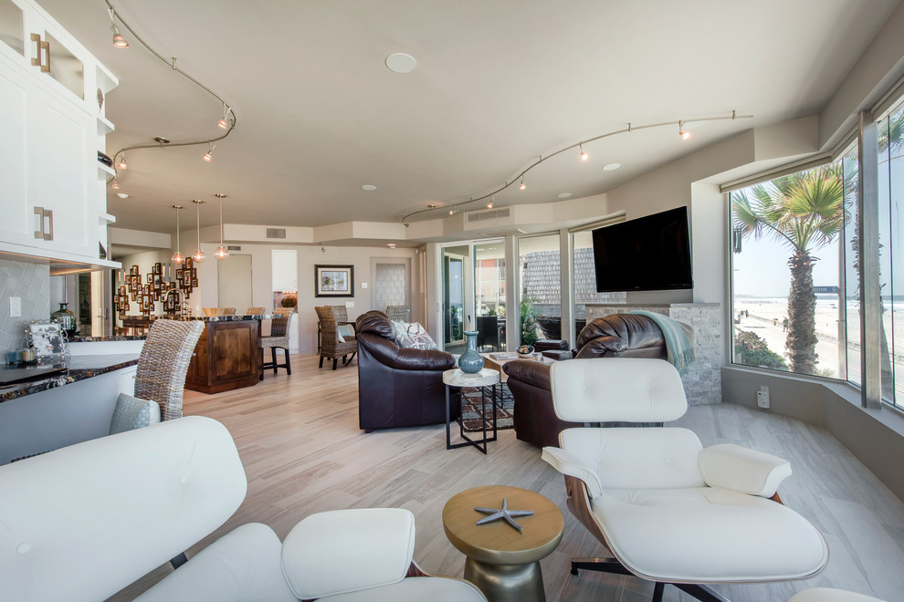 Large modern open plan living room in San Diego with beige walls, light hardwood flooring, a wall mounted tv, a standard fireplace and a stone fireplace surround.