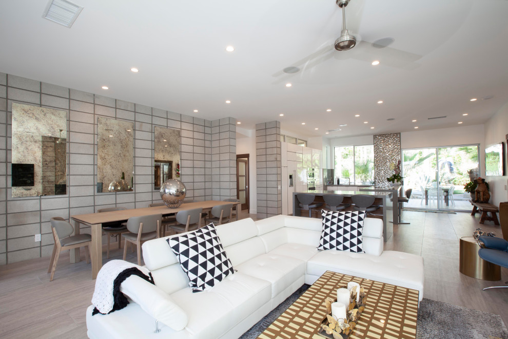 Idee per un ampio soggiorno minimalista aperto con pareti bianche, pavimento in gres porcellanato, cornice del camino in pietra, TV a parete e pavimento grigio
