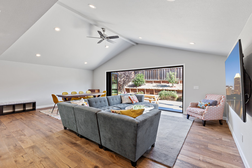 Großes, Offenes Modernes Wohnzimmer ohne Kamin mit grauer Wandfarbe, braunem Holzboden, TV-Wand und braunem Boden in San Francisco
