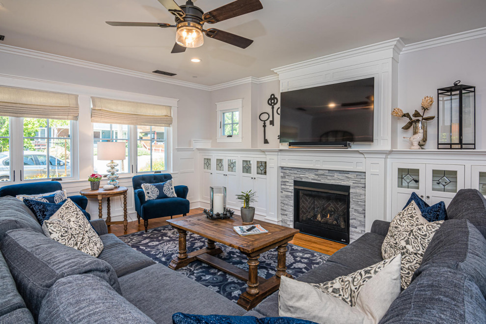 Medium sized traditional open plan living room in San Luis Obispo with a reading nook, white walls, light hardwood flooring, a standard fireplace, a stone fireplace surround, a wall mounted tv and brown floors.