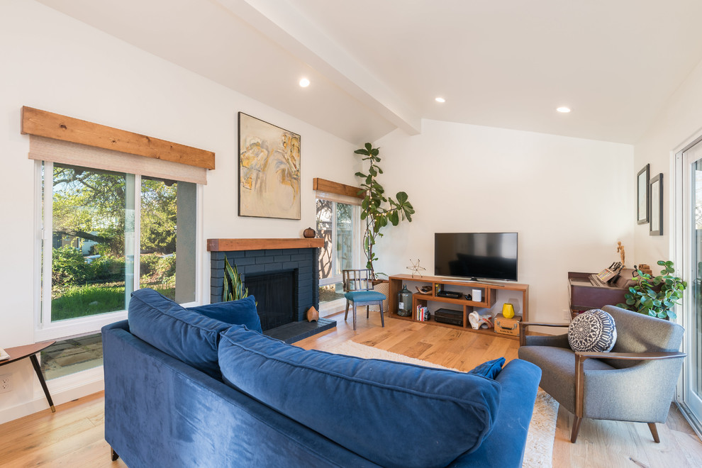 Example of a mid-sized 1960s open concept medium tone wood floor and brown floor living room design in San Luis Obispo with white walls, a standard fireplace and a brick fireplace