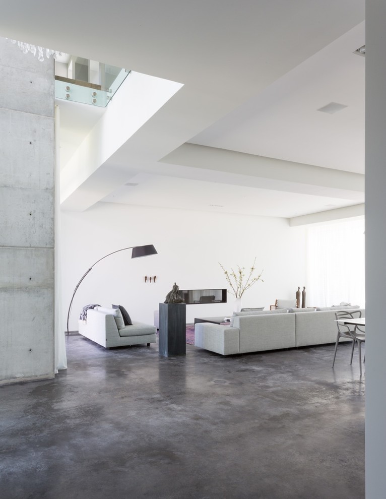 Inredning av ett modernt mellanstort allrum med öppen planlösning, med ett finrum, vita väggar, betonggolv, en spiselkrans i gips, en bred öppen spis och grått golv