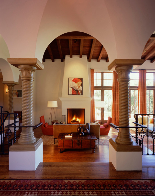 Großes Mediterranes Wohnzimmer mit beiger Wandfarbe, braunem Holzboden, Kamin und braunem Boden in Santa Barbara