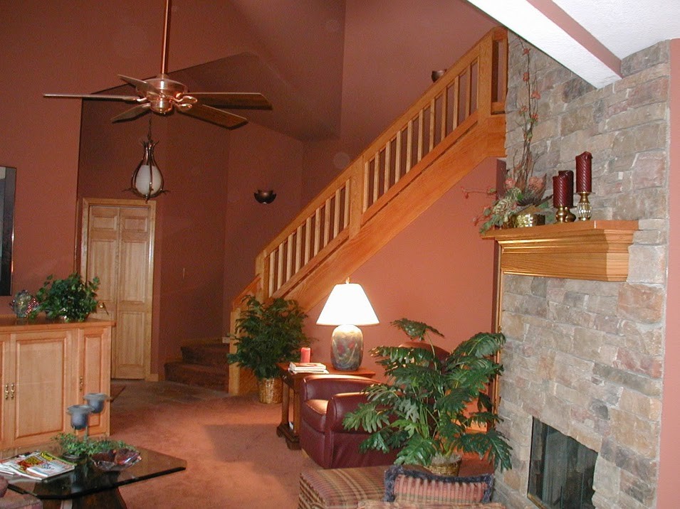 Réalisation d'un petit salon chalet avec un mur rouge, moquette, une cheminée standard, un manteau de cheminée en pierre et un sol rouge.