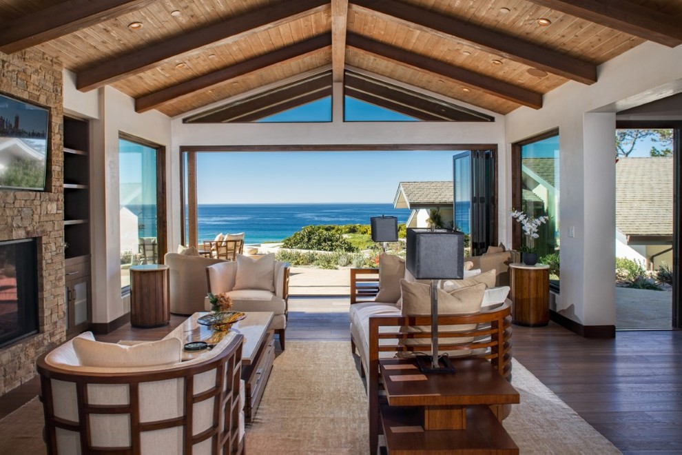 Inspiration for a large beach style open plan living room in San Francisco with a standard fireplace, a stone fireplace surround, a wall mounted tv, white walls and medium hardwood flooring.