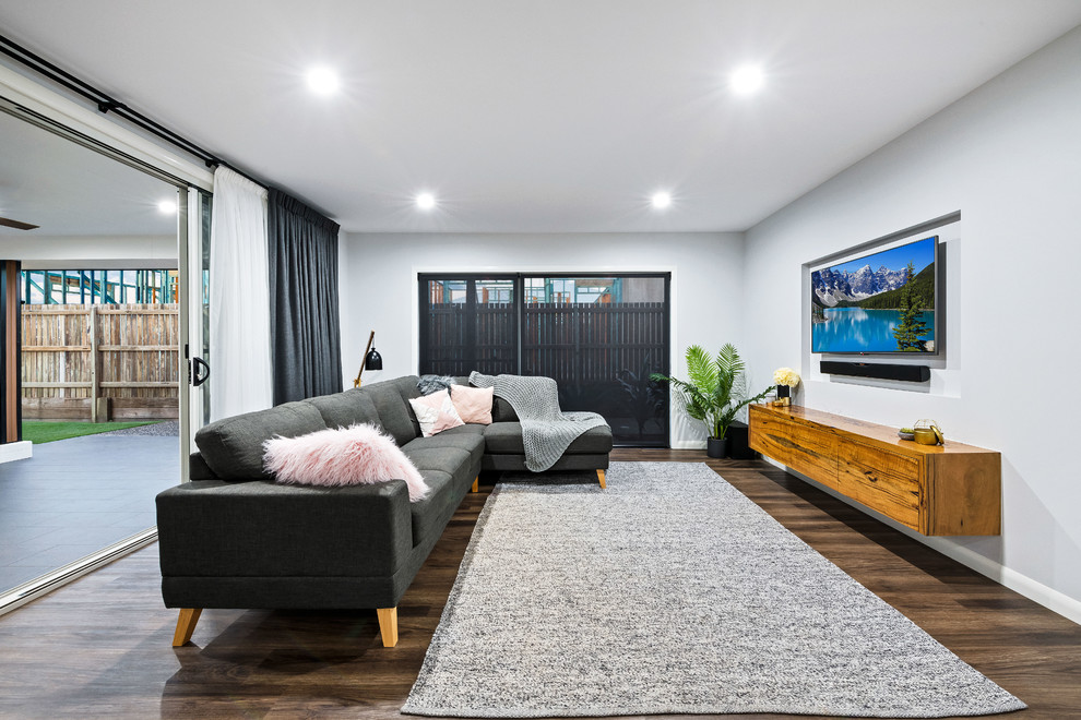 Свежая идея для дизайна: открытая гостиная комната среднего размера в современном стиле с белыми стенами, полом из ламината, телевизором на стене и коричневым полом без камина - отличное фото интерьера