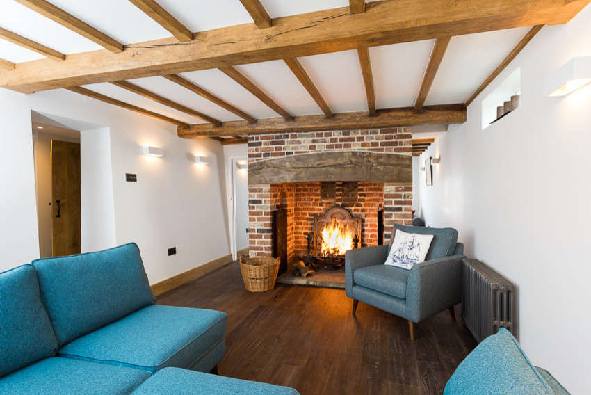 Small mountain style enclosed dark wood floor and brown floor living room photo in Kent with white walls, a standard fireplace, a brick fireplace and a wall-mounted tv