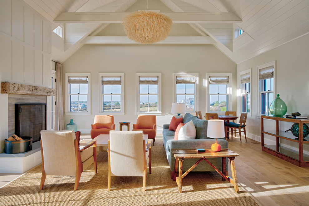 他の地域にあるビーチスタイルのおしゃれなリビング (ベージュの壁、淡色無垢フローリング、標準型暖炉、ベージュの床、青いソファ) の写真