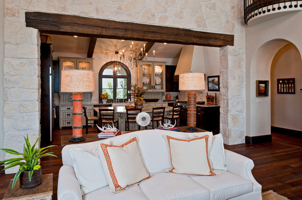 Geräumiges, Repräsentatives, Offenes Mediterranes Wohnzimmer mit weißer Wandfarbe, braunem Holzboden, Kamin und Kaminumrandung aus Stein in Austin