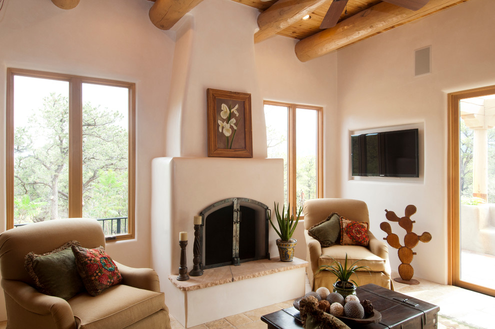 Cette photo montre un salon sud-ouest américain de taille moyenne et ouvert avec une salle de réception, un mur beige, une cheminée standard, un manteau de cheminée en plâtre et un téléviseur fixé au mur.