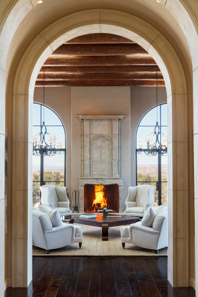 Expansive mediterranean formal open plan living room in Albuquerque with beige walls, dark hardwood flooring, a standard fireplace, a stone fireplace surround and no tv.