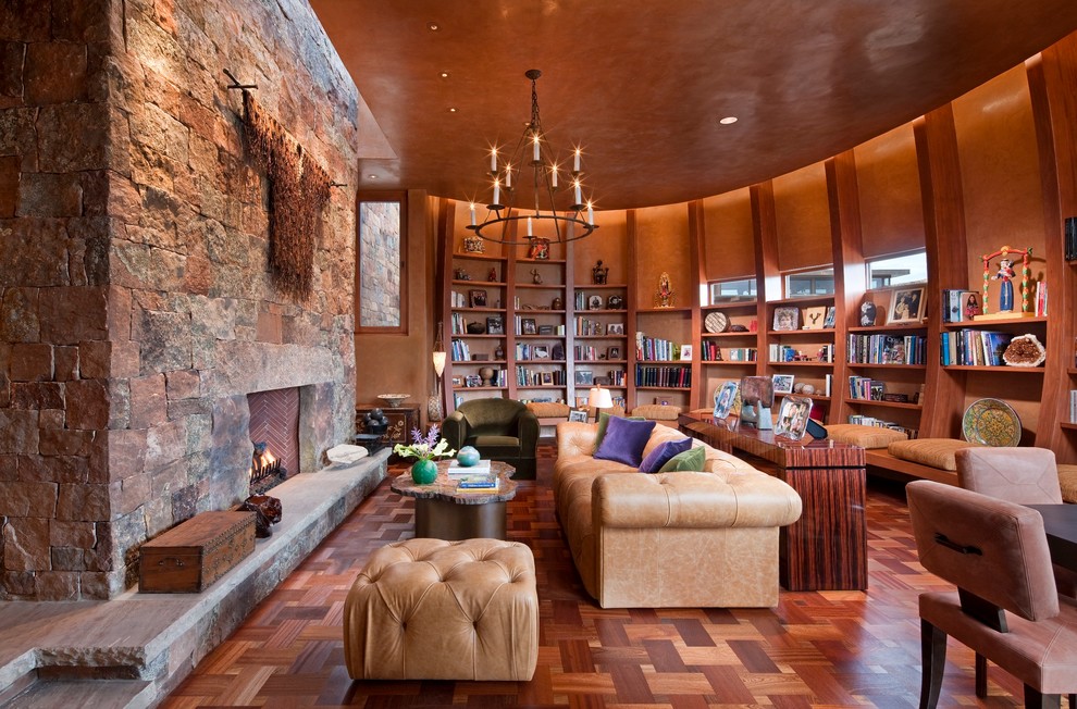 Exempel på ett mycket stort amerikanskt separat vardagsrum, med ett bibliotek, orange väggar, en standard öppen spis, mörkt trägolv, en spiselkrans i sten och brunt golv
