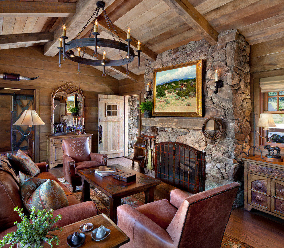 Exemple d'un grand salon sud-ouest américain ouvert avec parquet foncé, une cheminée standard, un manteau de cheminée en pierre, un mur marron et aucun téléviseur.