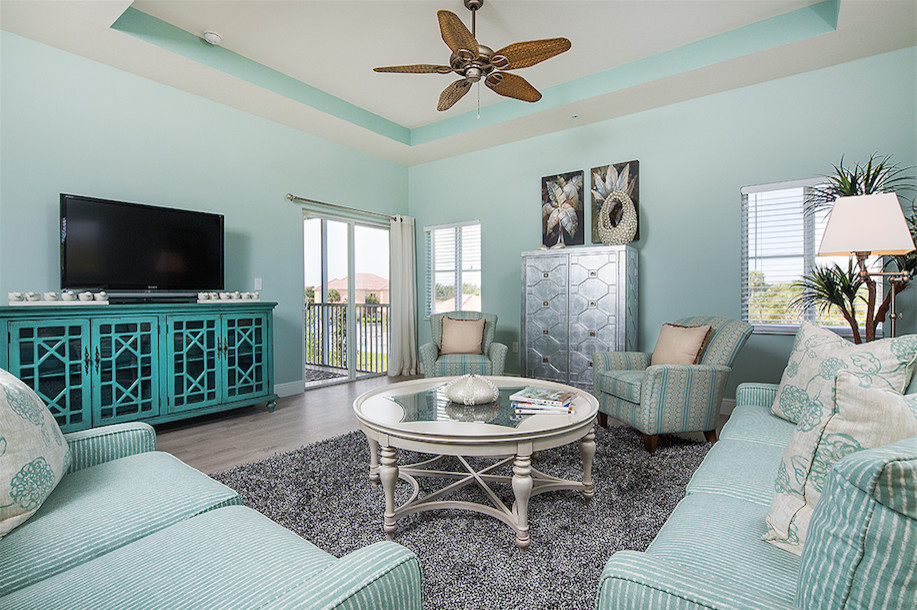 На фото: парадная, изолированная гостиная комната среднего размера в морском стиле с синими стенами, темным паркетным полом, отдельно стоящим телевизором и коричневым полом без камина
