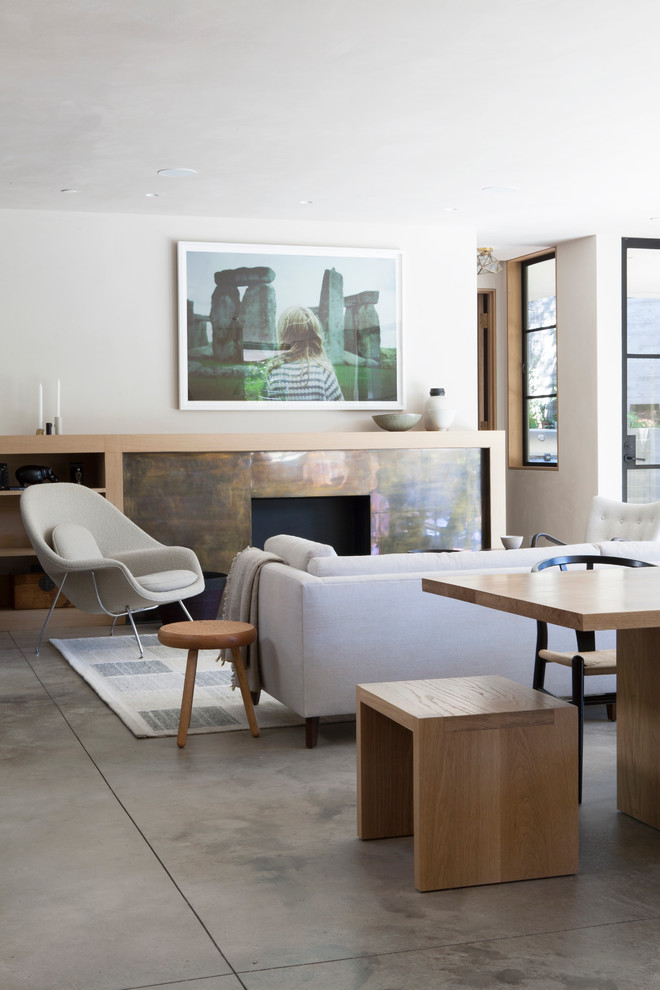 Стильный дизайн: открытая гостиная комната в стиле неоклассика (современная классика) с белыми стенами, бетонным полом и стандартным камином без телевизора - последний тренд