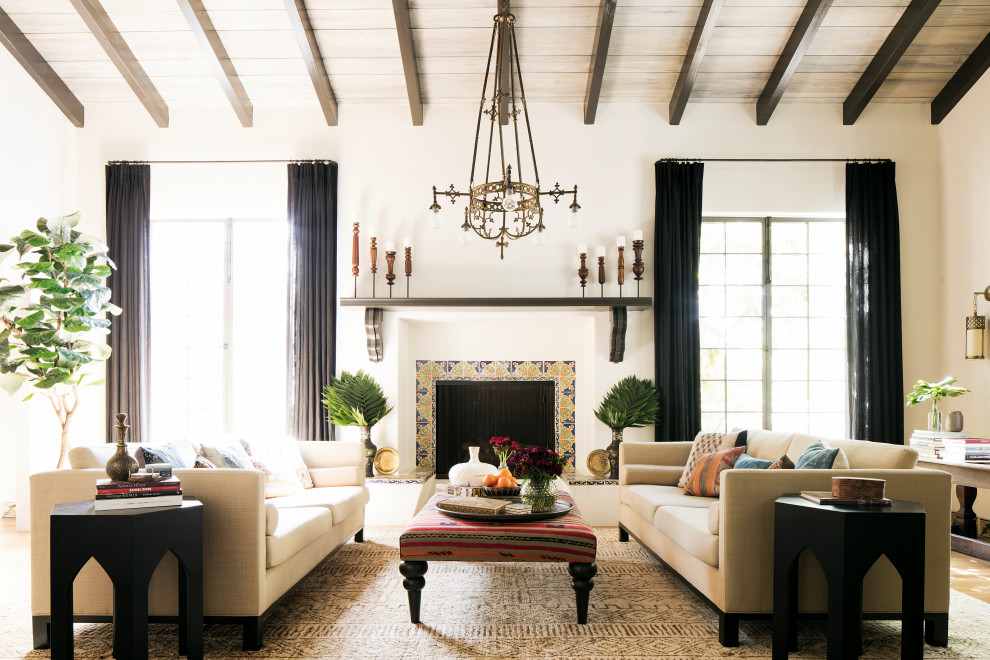 Mediterranes Wohnzimmer mit weißer Wandfarbe, braunem Holzboden, Kamin, gefliester Kaminumrandung, braunem Boden, freigelegten Dachbalken, gewölbter Decke und Holzdecke in Los Angeles