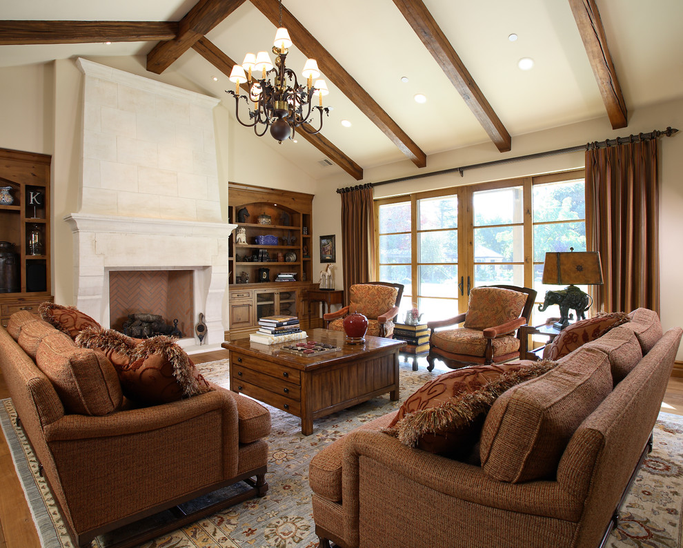 Стильный дизайн: гостиная комната в классическом стиле с бежевыми стенами, паркетным полом среднего тона, стандартным камином и коричневым диваном - последний тренд